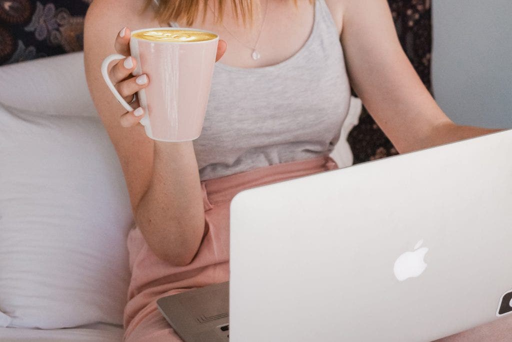 Mulher sentada no seu sofá com o seu computador